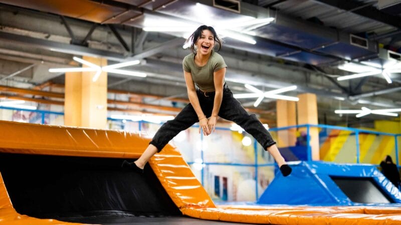 Woman jumping on a trampoline and smiling.