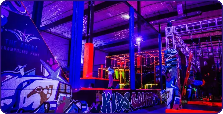 Neon-lit indoor trampoline park with obstacles.