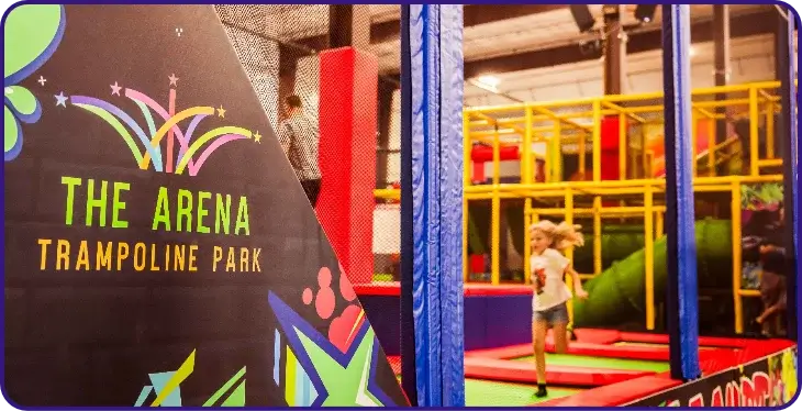 The Arena Trampoline Park sign with children playing in the background.